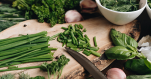 A picture of a chopping board showing a knife and herbs being chopped