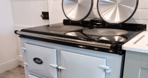 A picture of a blue reconditioned Aga cooker with the lids up and showing hotplates